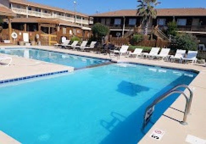 Outdoor swimming pool with blue water, lounge chairs, and a two-story resort building in the background