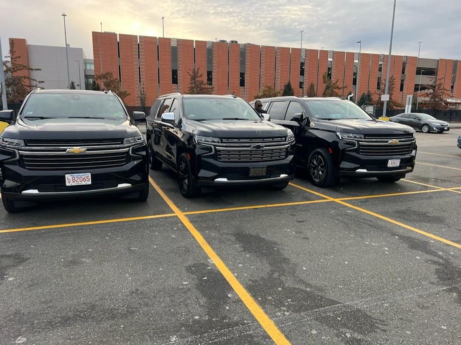 Three identical black Chevrolet SUVs parked side-by-side in a paved parking lot with a brick building in the background.