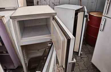 White discarded refrigerators outdoors; one open, others nearby.