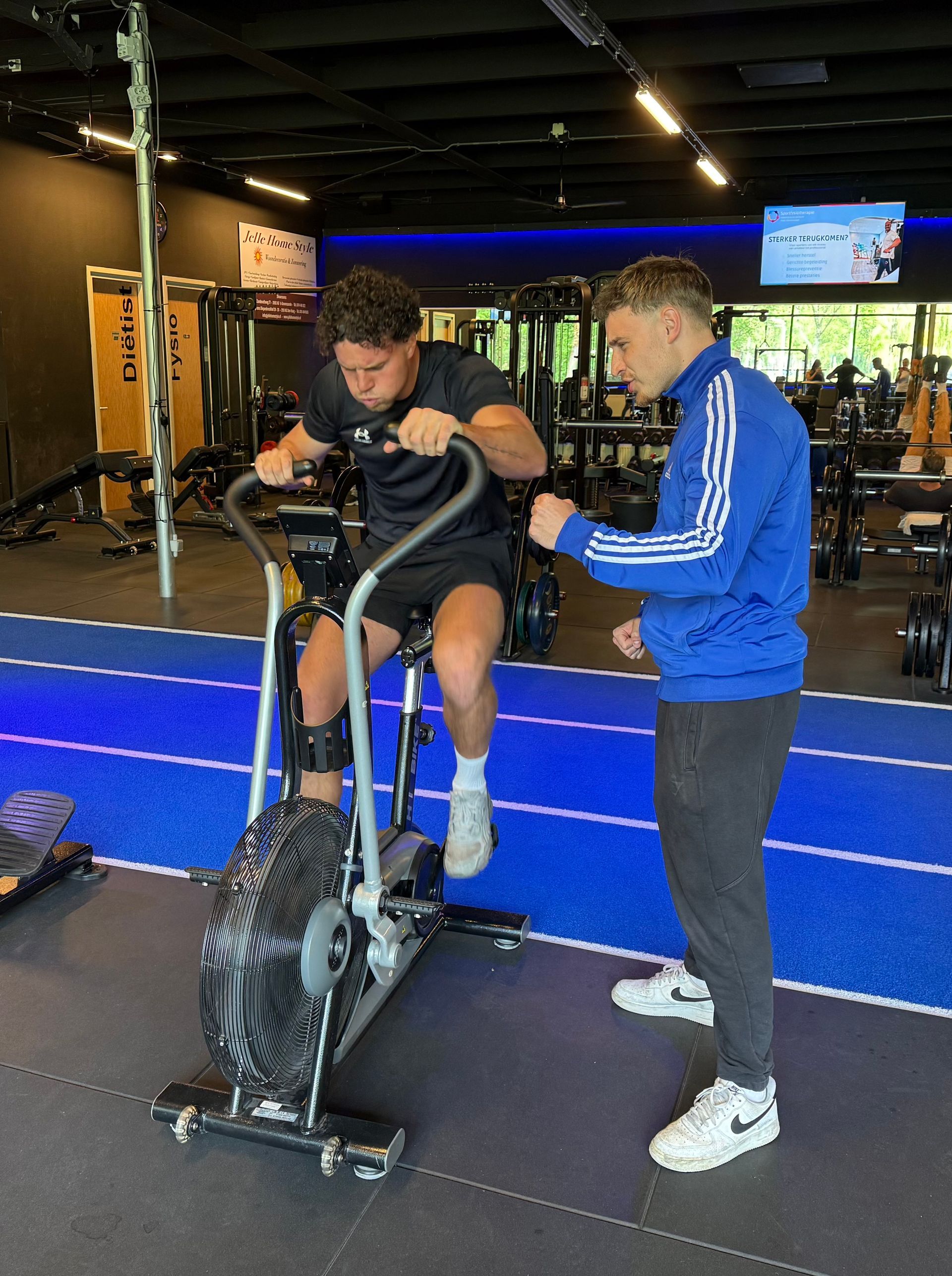 In een moderne sportschool met een blauwe baan en zwarte fitnessapparatuur.