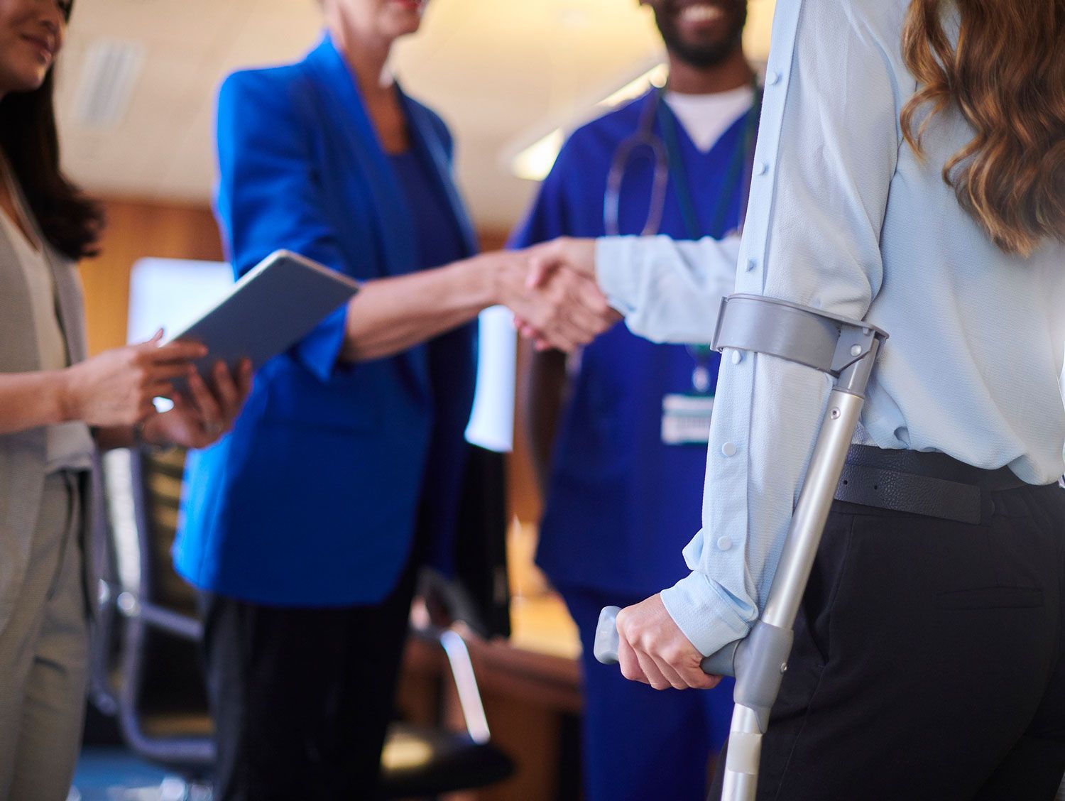 A woman with crutches is shaking hands with a doctor.