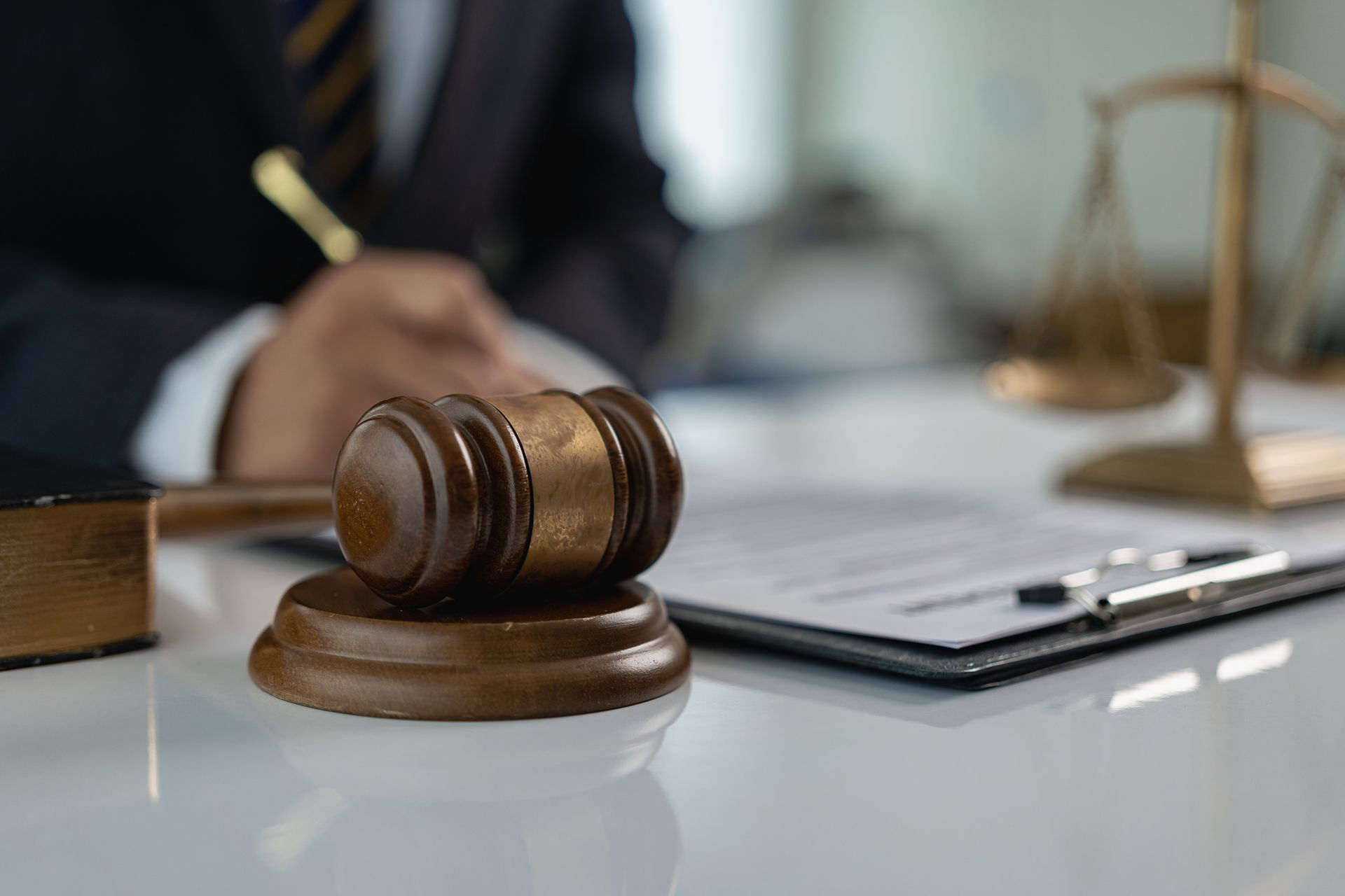 A judge 's gavel is sitting on a table next to a clipboard and scales of justice. A judge 's gavel is sitting on a table next to a clipboard and scales of justice.