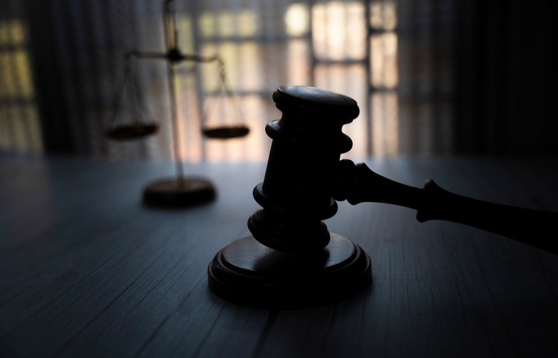 A judge 's gavel is sitting on a wooden table in front of a scale of justice. A judge 's gavel is sitting on a wooden table in front of a scale of justice.