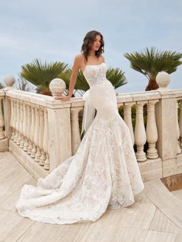 Bride in a strapless lace mermaid wedding dress leaning on a stone railing.