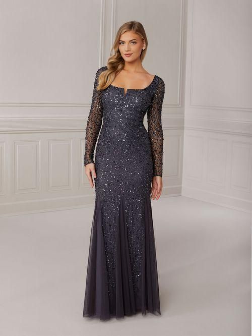 Woman in a long, navy blue sequined gown with long sleeves, standing in a room.