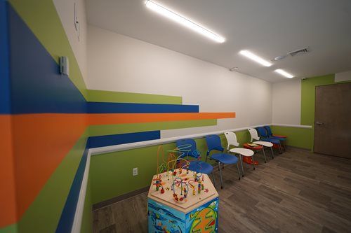 Colorful children’s playroom with chairs, a toy table, and striped wall accents
