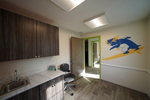 Bright kitchenette with wood cabinets, sink, table, and a blue bull mural on a white wall.