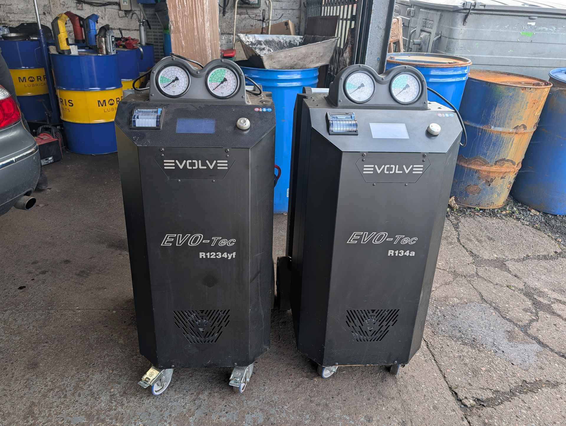 Two black Evolve air compressors with gauges and wheels in a workshop yard.