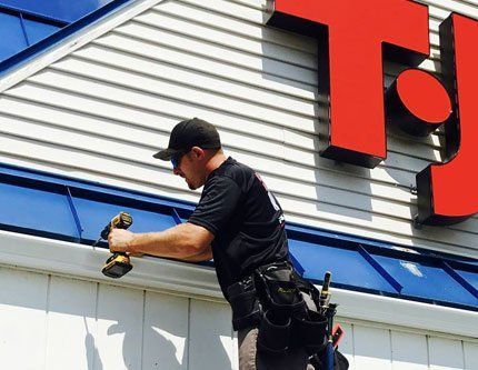 Certified Technician Installing Seamless Gutters on Local Business