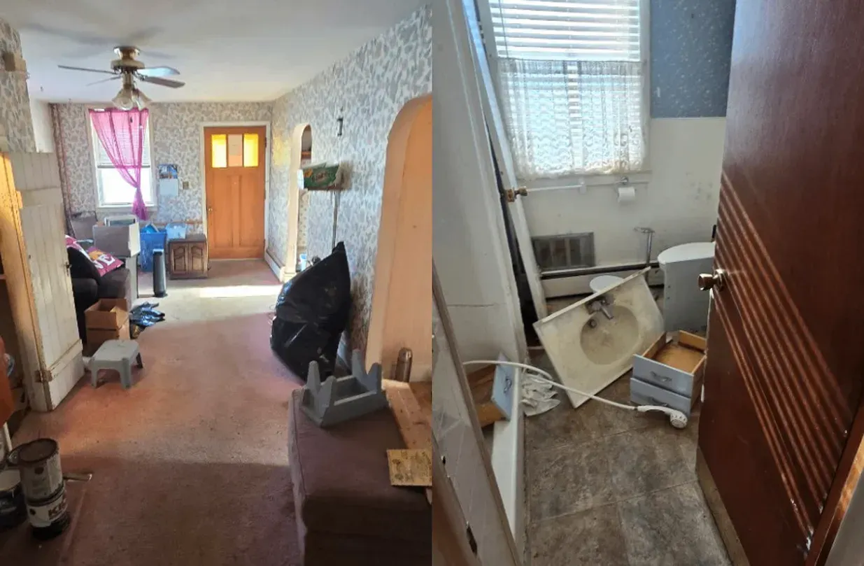 Cluttered living room with overturned chair, leaning table, and broken window blinds near a front door.