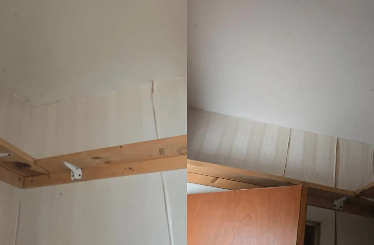 Interior wall with a damaged ceiling seam and exposed wooden beam above a doorway.
