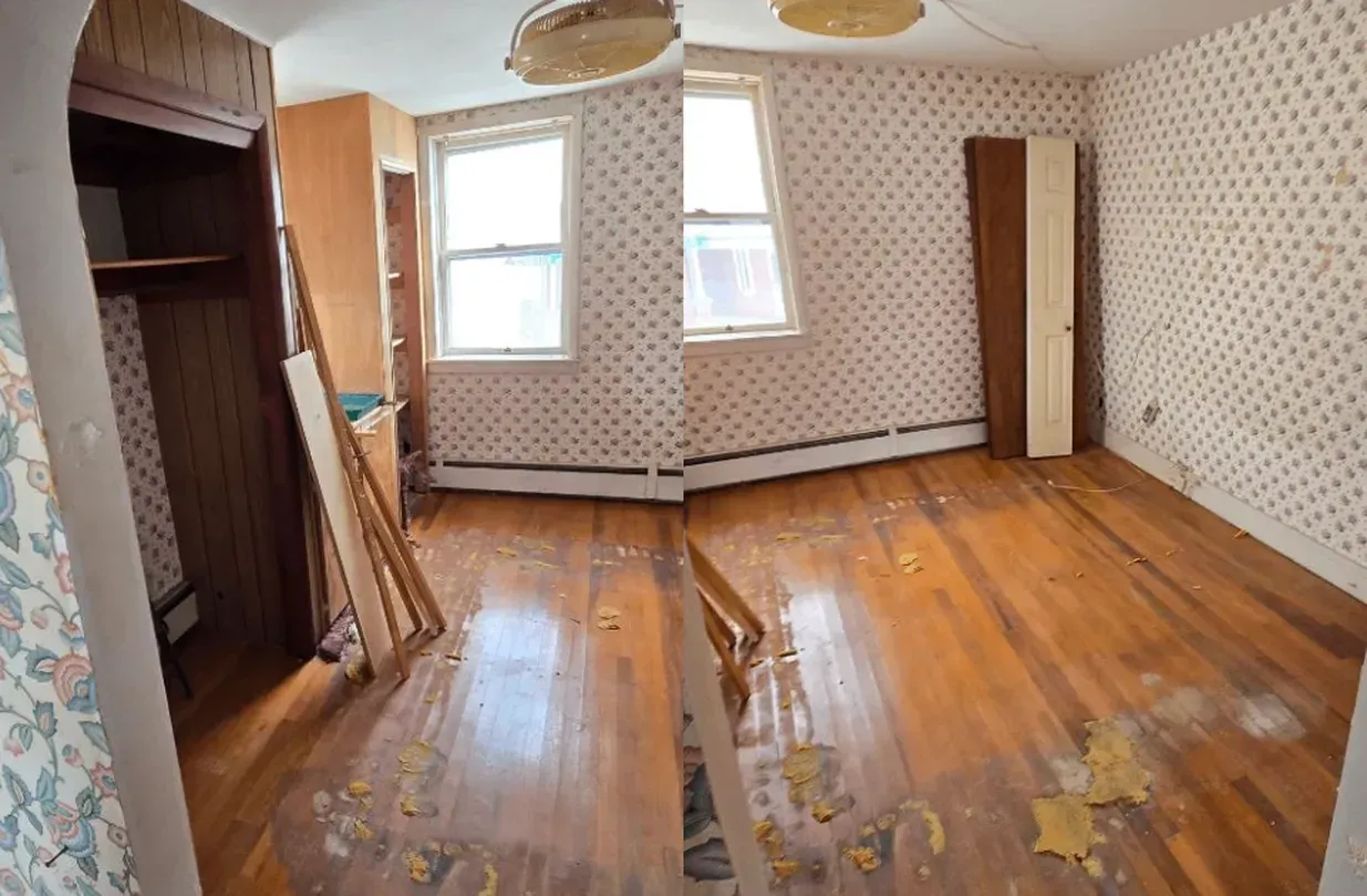 Empty room with worn wooden floor, patterned wallpaper, two windows, and an open closet area.