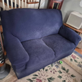 Blue loveseat in a living room beside a floral rug and a space heater