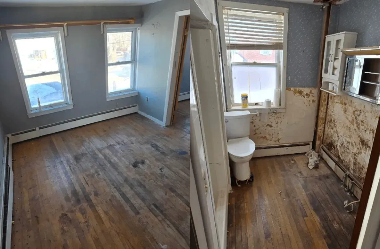 Empty room and small bathroom under renovation with exposed walls, wood floors, and a toilet by the window