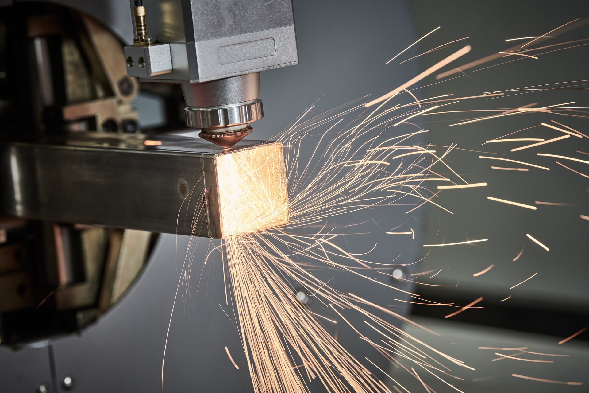 Metal cutting machine sparking as it cuts a steel beam in a workshop