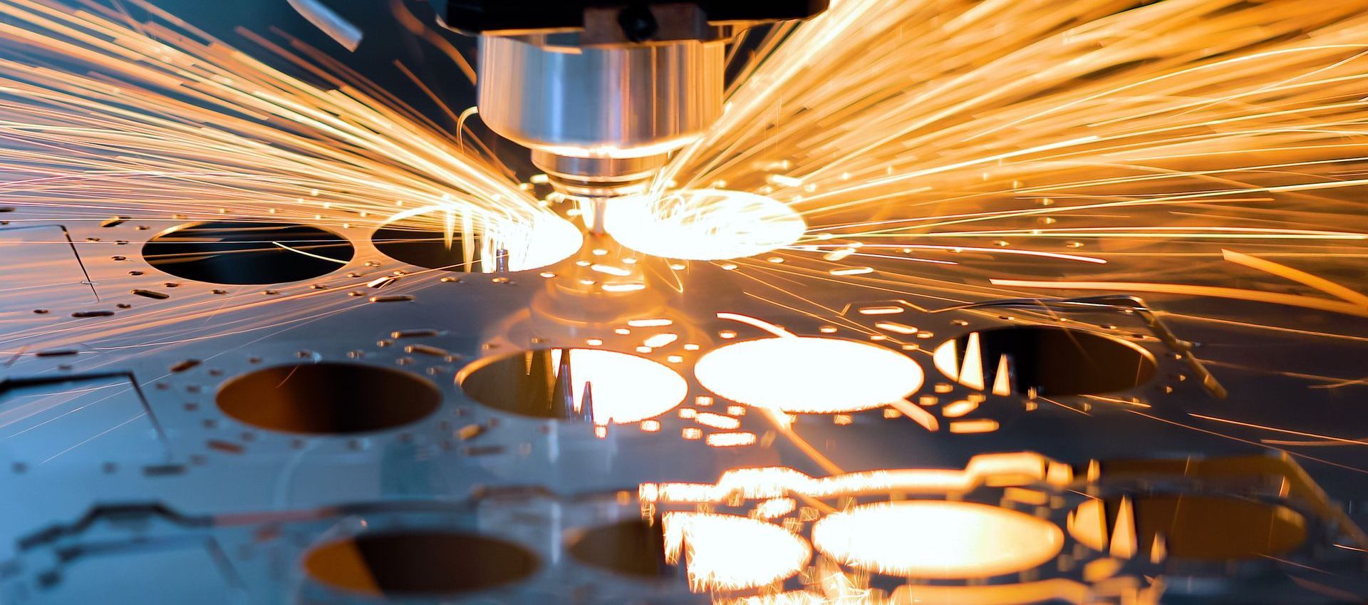Laser cutting metal sheet with bright sparks flying in a factory workshop