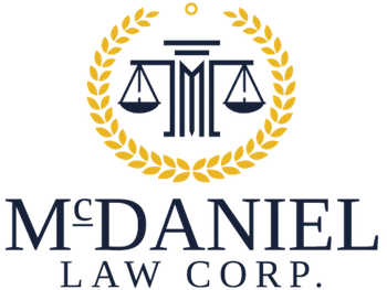 Logo for McDaniel Law Corp. featuring a gold laurel wreath framing a stylized pillar and scales of justice icon.