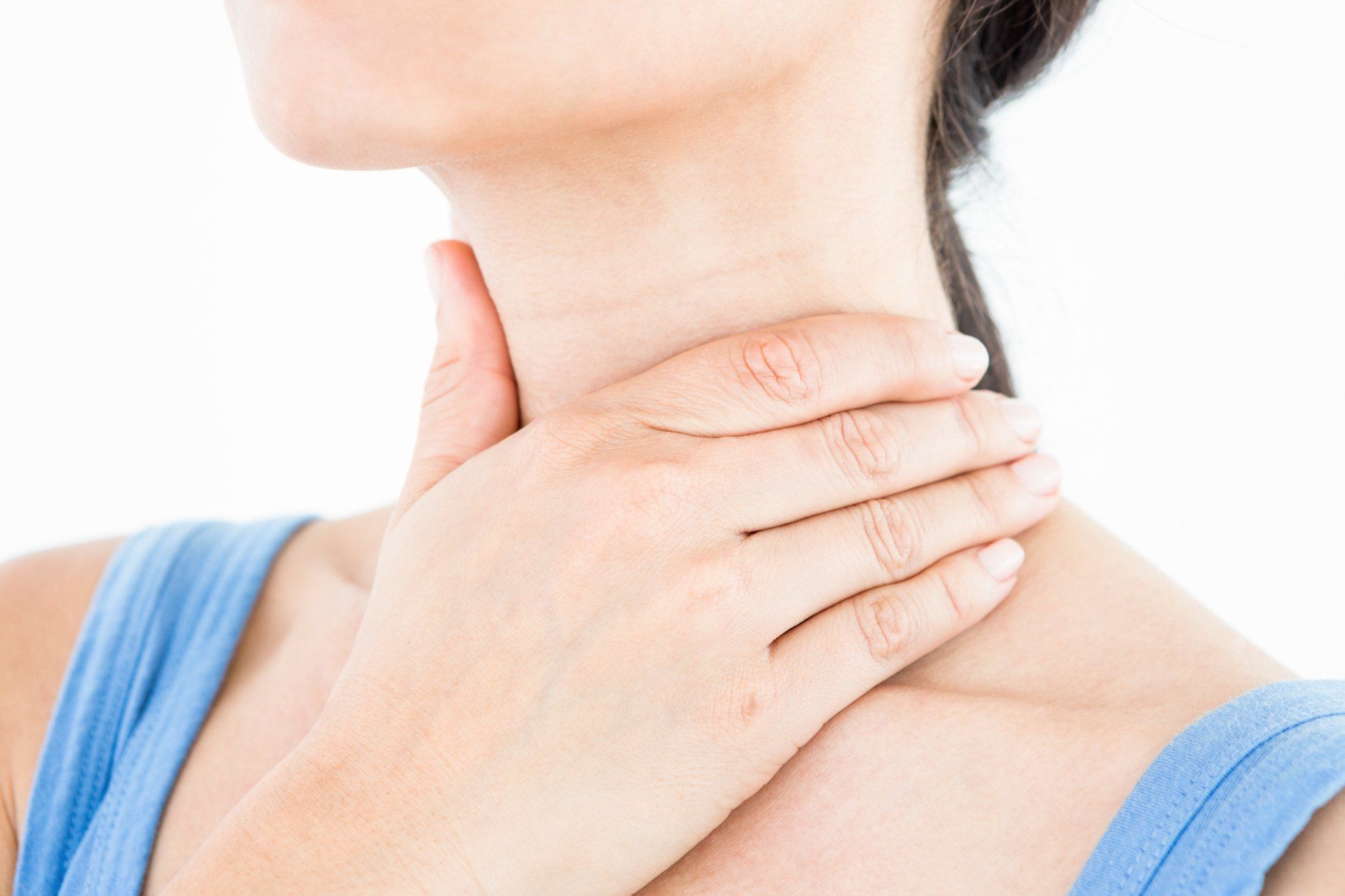A woman is holding her neck with her hands because she has a sore throat.