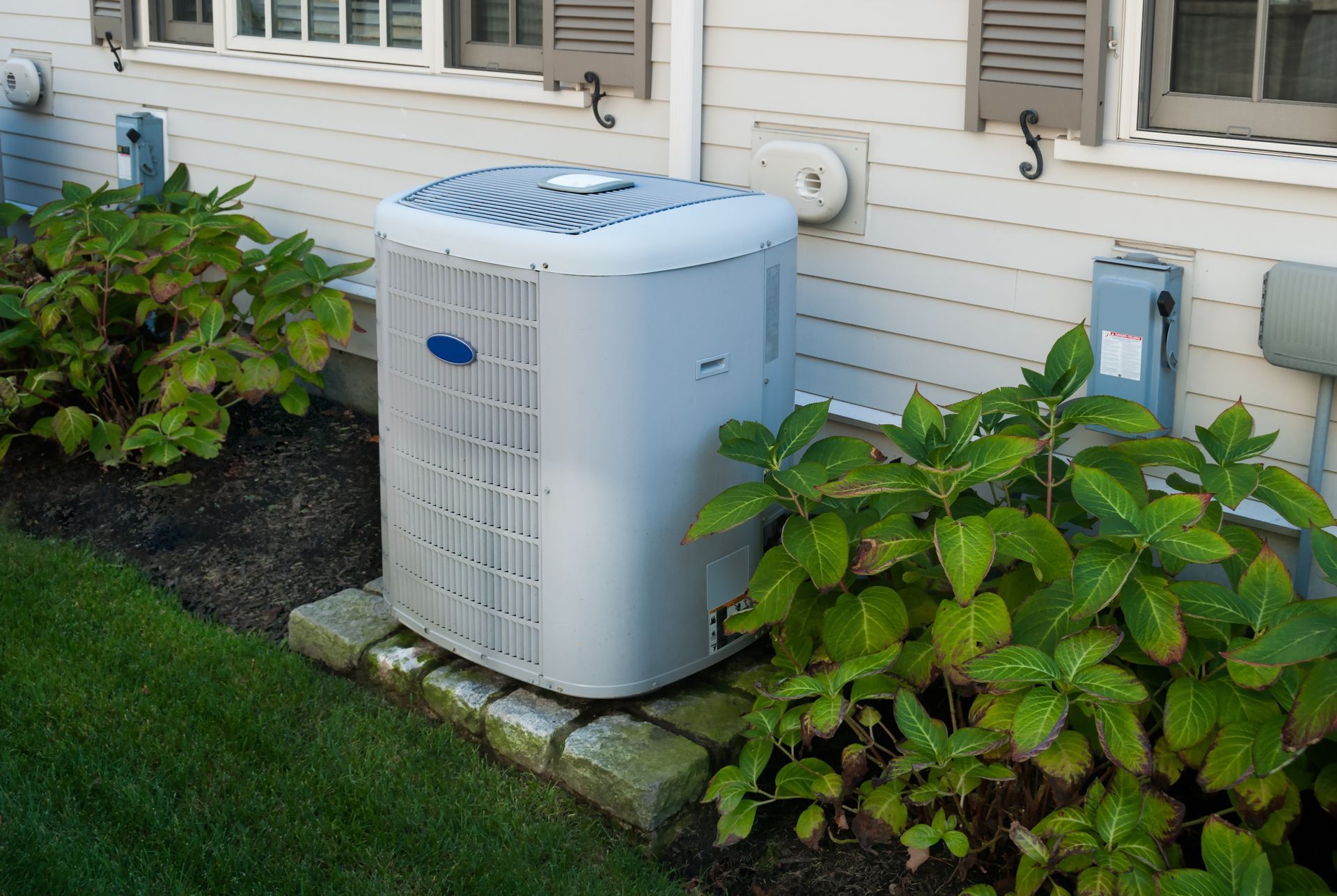 A white air conditioner is sitting on the side of a house.