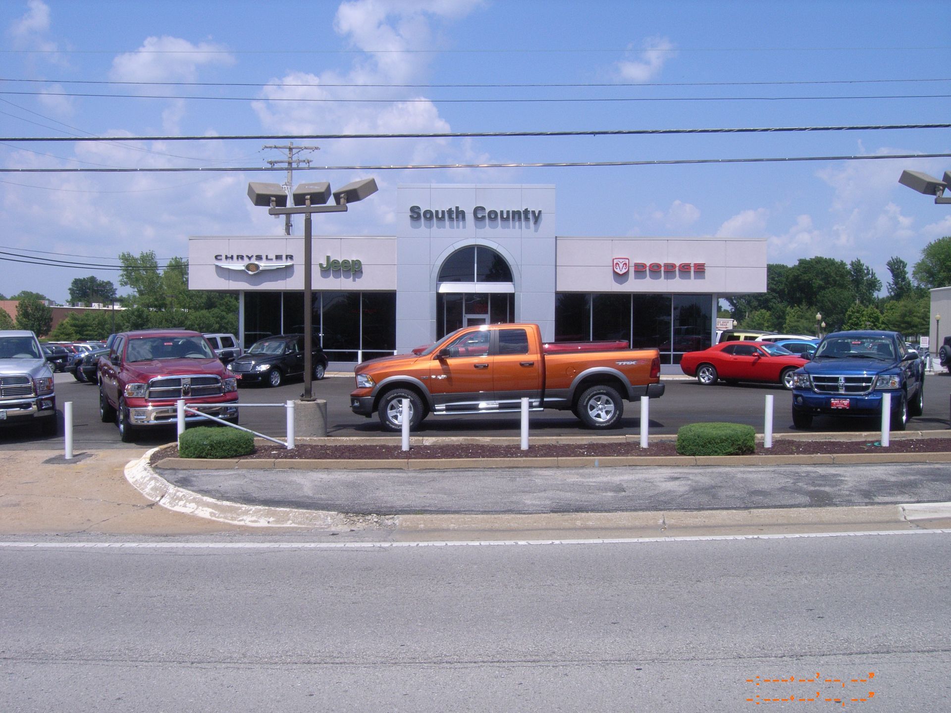 Car dealership lot with several cars parked in front of the South County showroom.