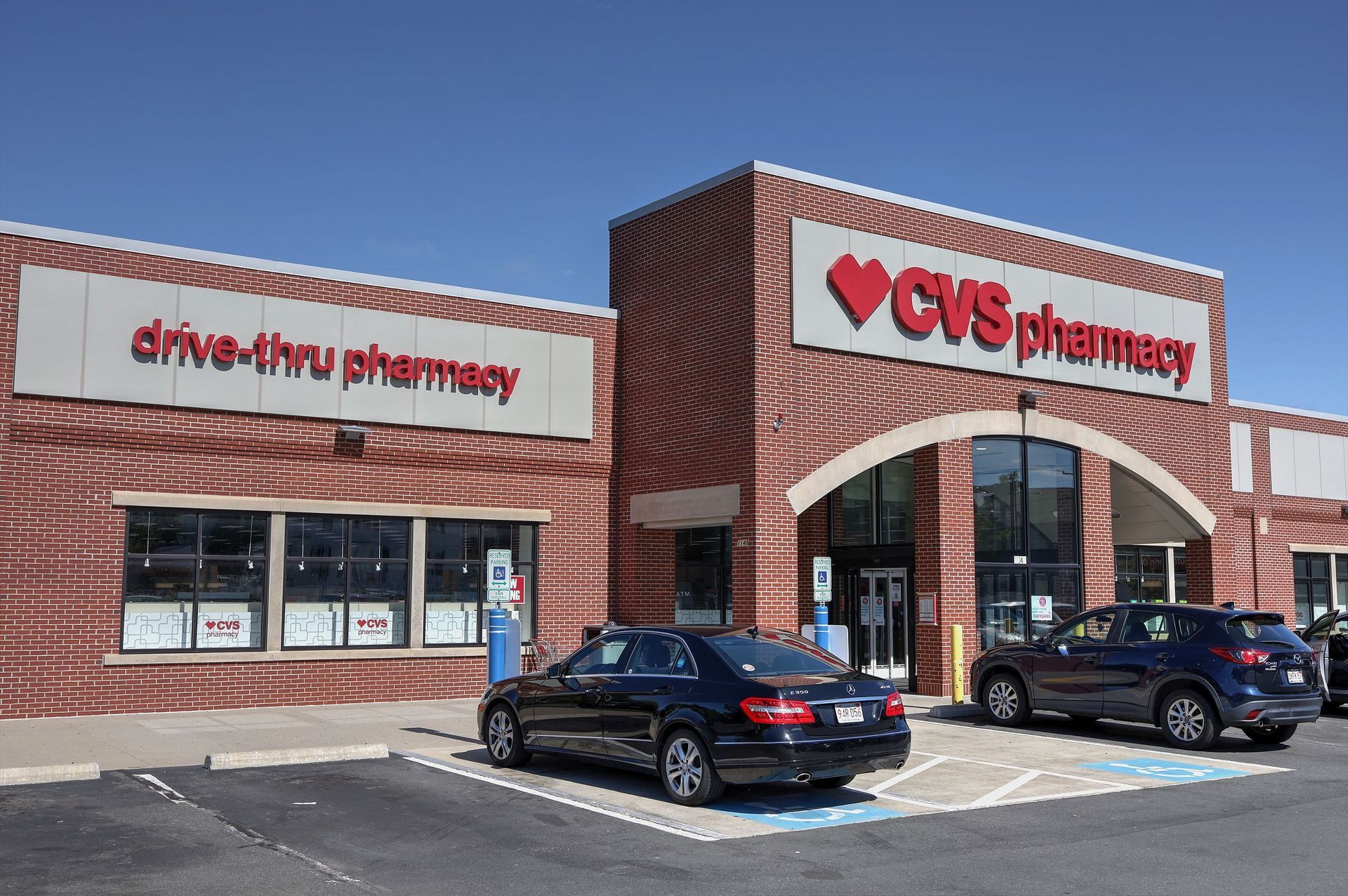 CVS pharmacy storefront with brick exterior and parked cars on a sunny day