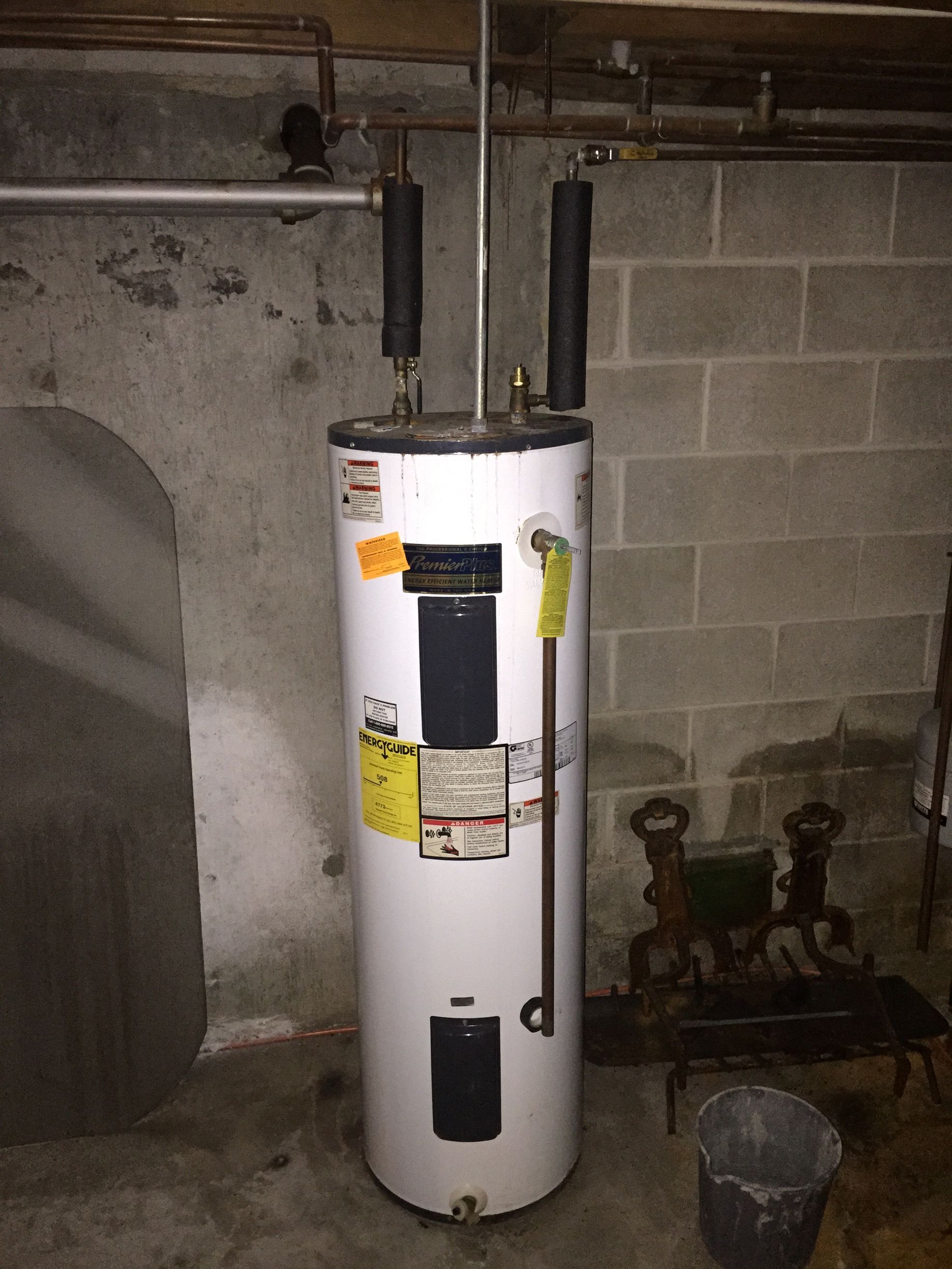 Person repairing a white gas furnace, using a screwdriver, indoors.