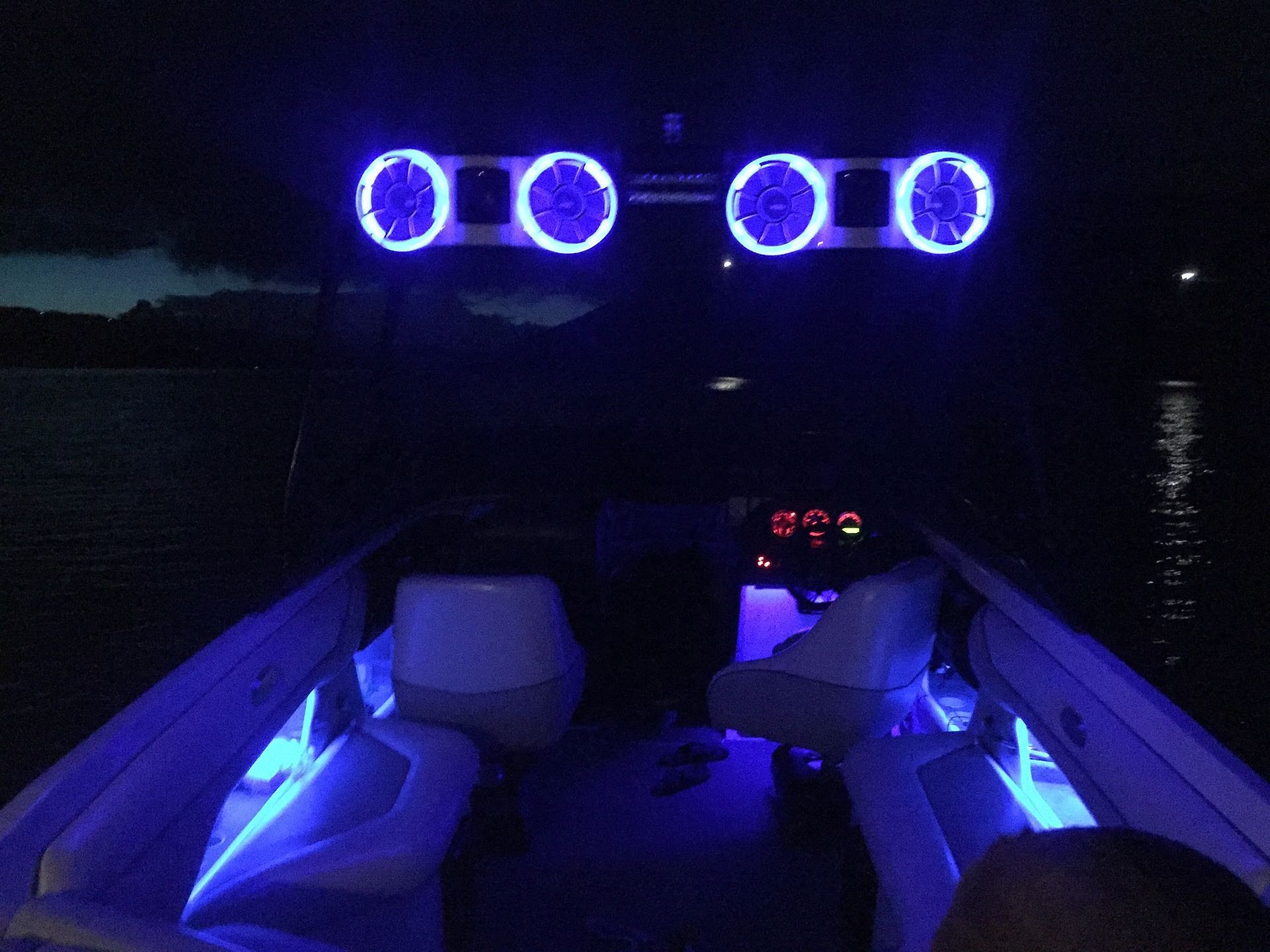 Illuminated boat cabin at night with blue lights and glowing speakers on the deck