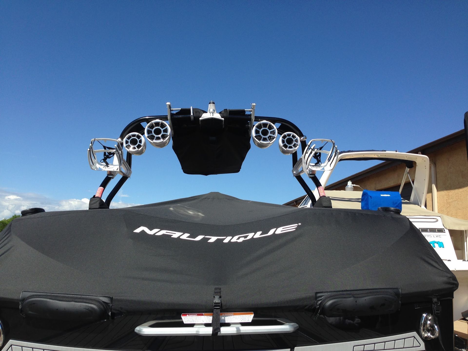 Black vehicle with a roof rack and mounted lights under a clear blue sky, seen from the front