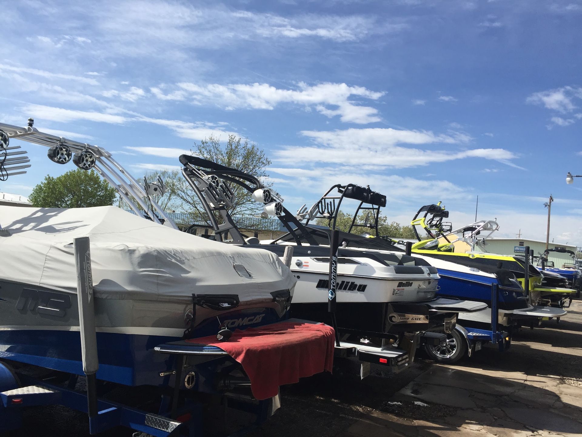 Boat storage lot with covered boats and wakeboard boats lined up under a blue sky