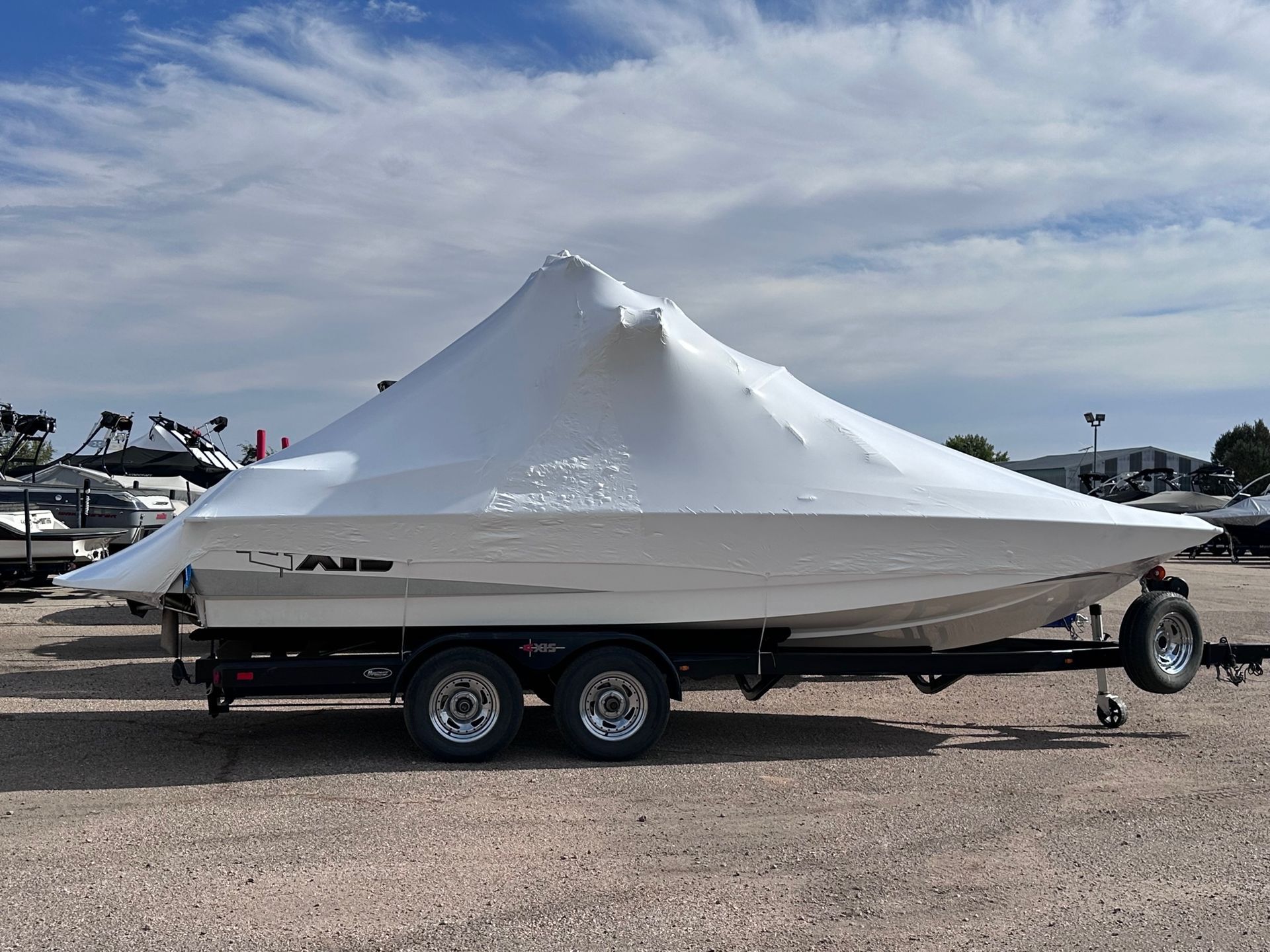White boat on a trailer at a boatyard under a cloudy sky