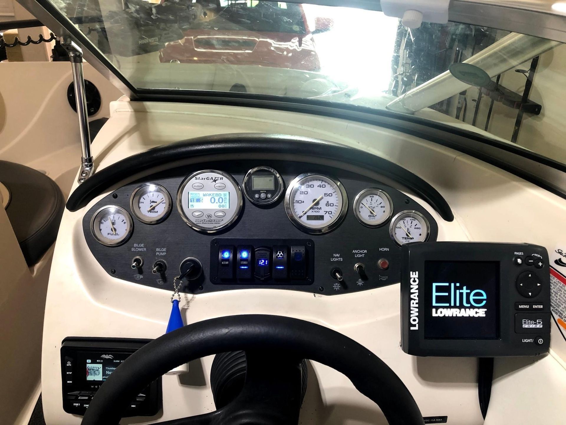 Boat helm with steering wheel, gauges, and controls, viewed from the driver’s seat