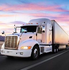 White semi-truck hauling a trailer on a highway at sunset