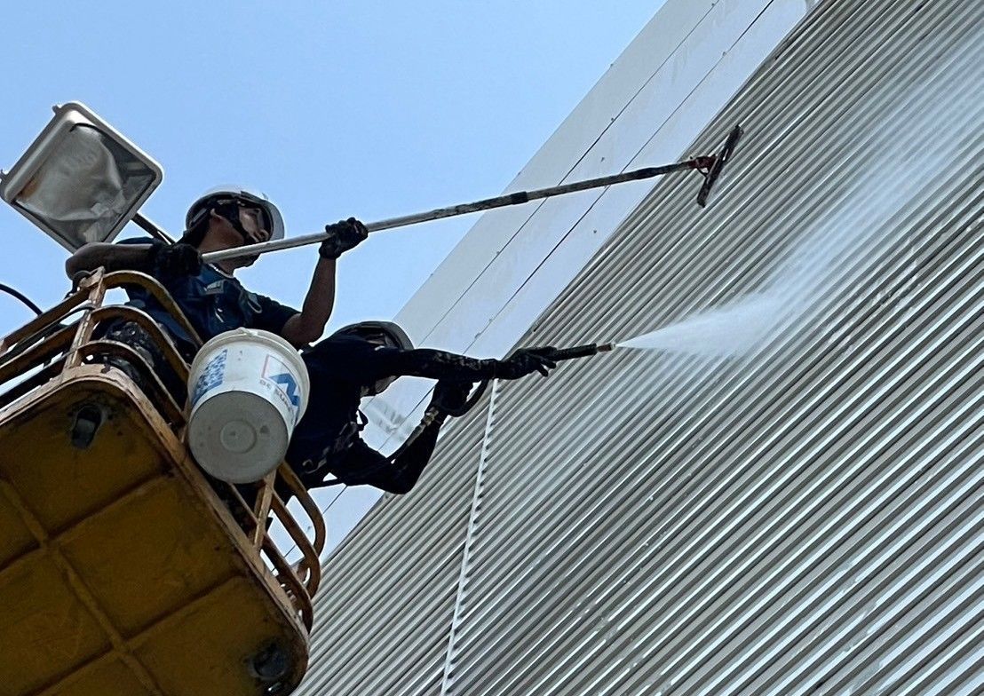 A man is cleaning a building with a high pressure washer.
