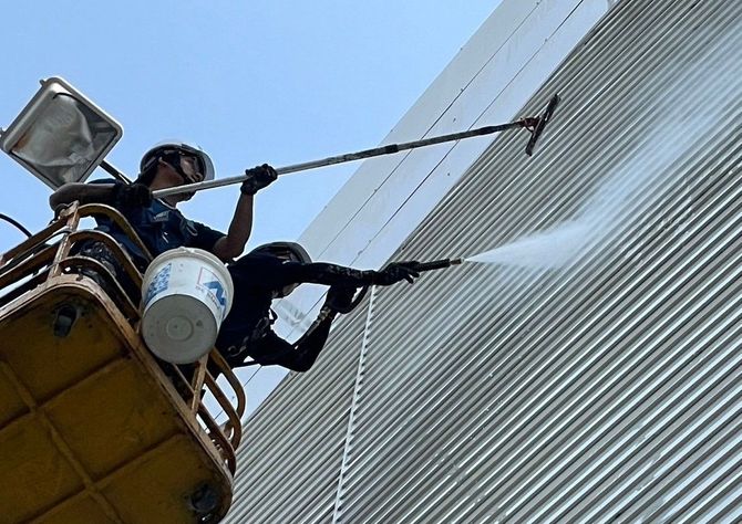 A man is cleaning a building with a high pressure washer.
