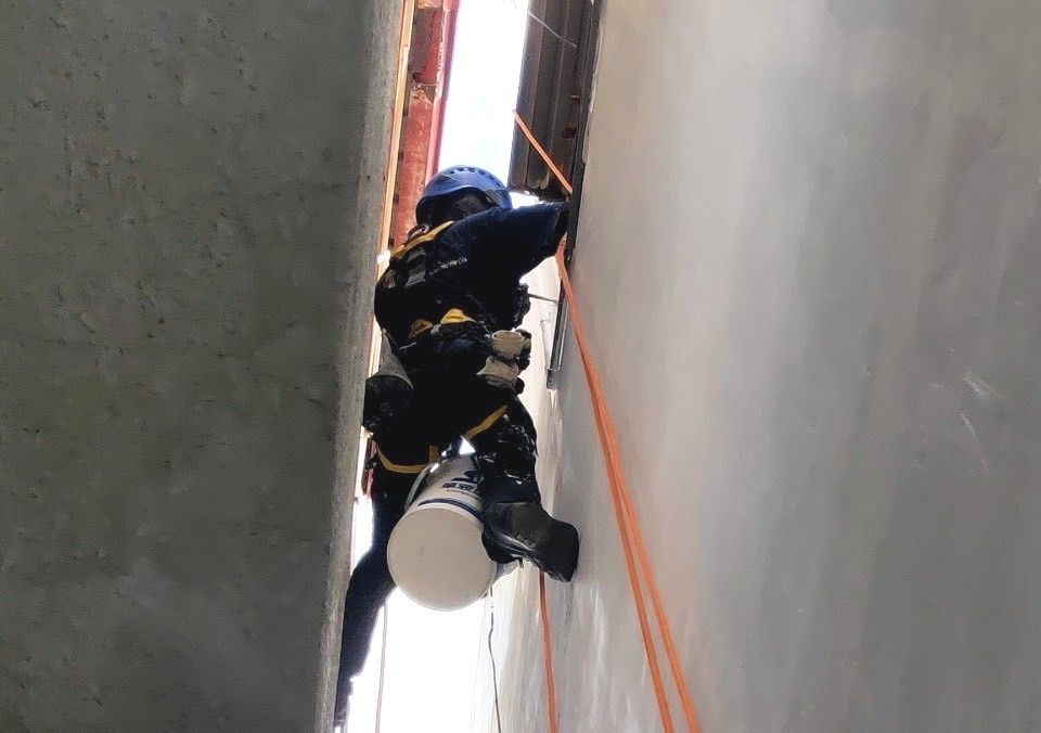 A man is climbing up a wall with a bucket.