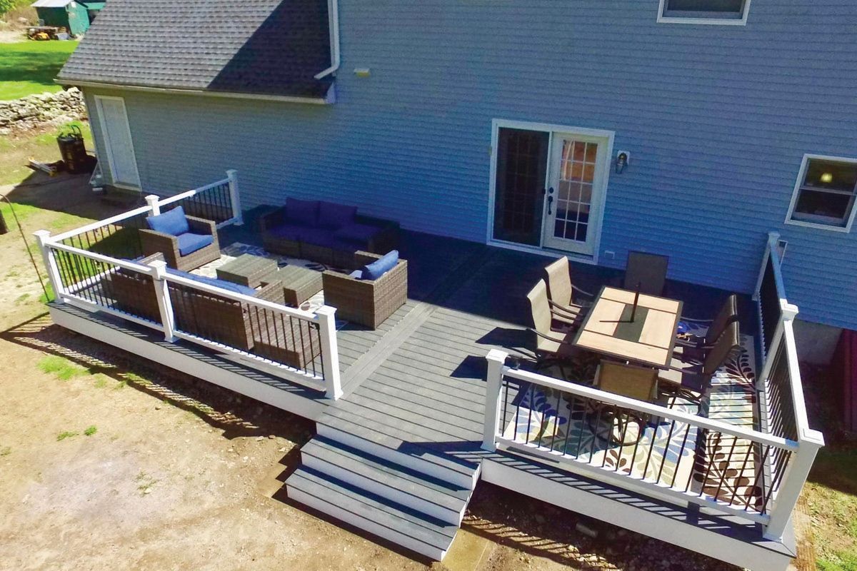 An aerial view of a deck with a table and chairs in front of a house.