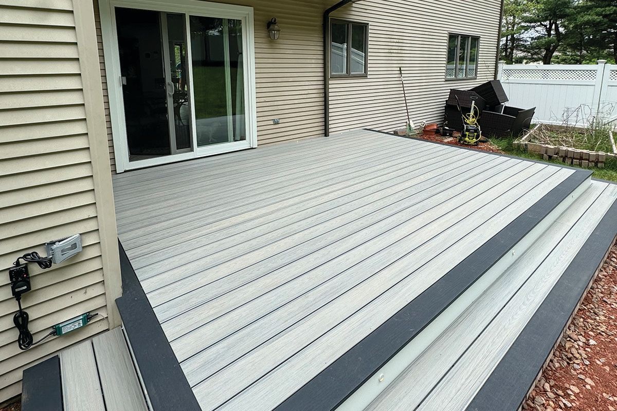 A white deck with a black border is sitting in front of a house.