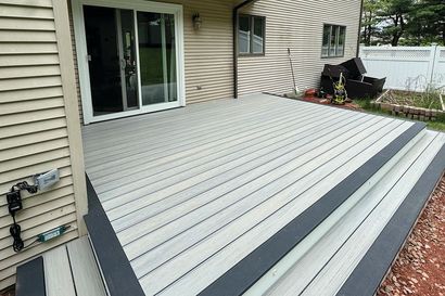 A white deck with a black border is sitting in front of a house.