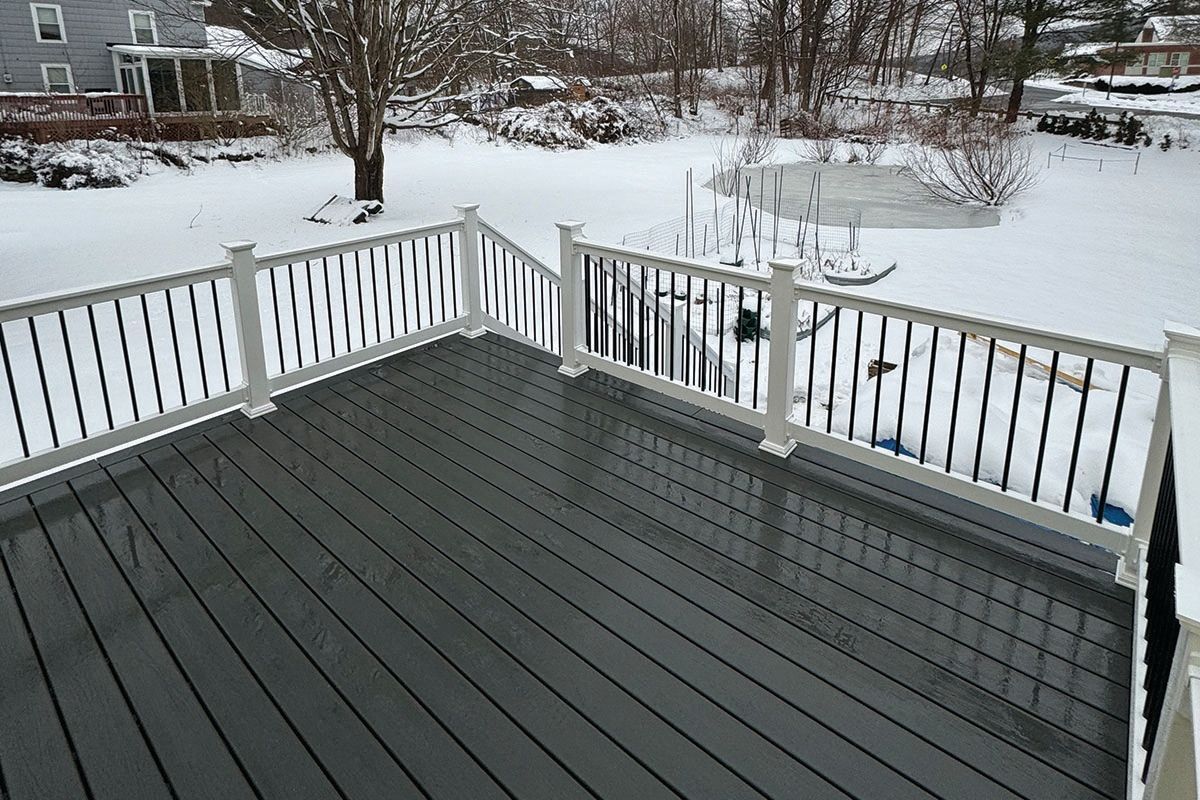 A deck with a white railing is covered in snow.