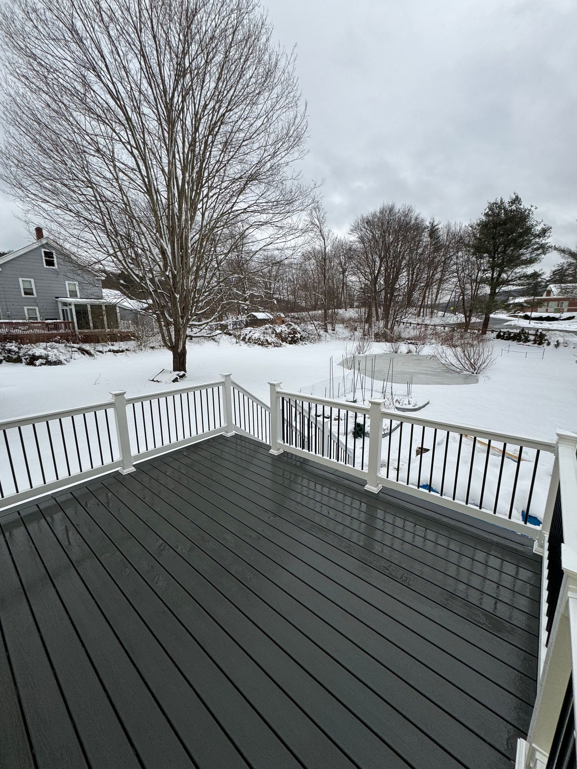 A deck with a white railing is covered in snow.