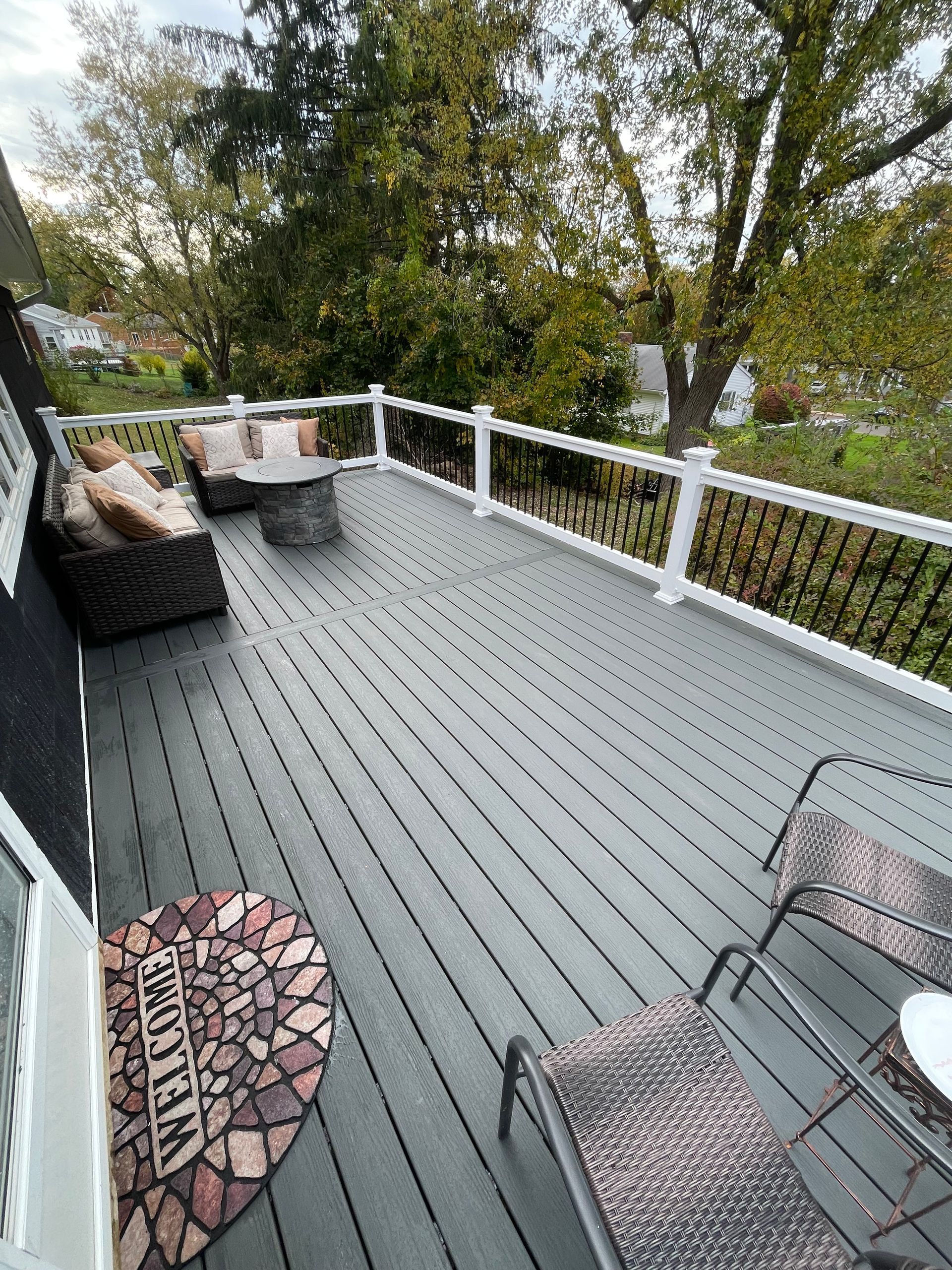 A deck with a couch , chairs , a table and a fire pit.