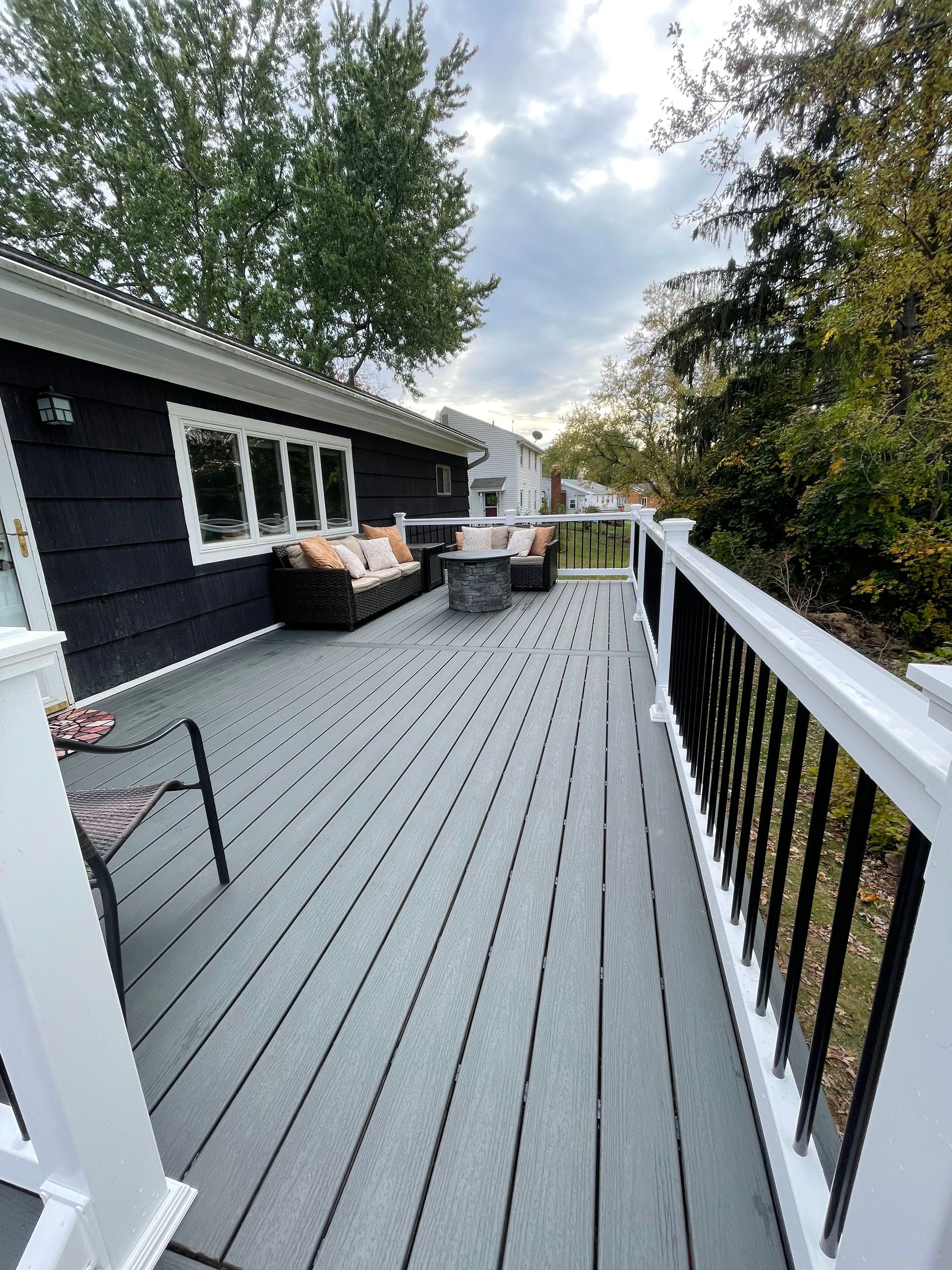 A large deck with a black house in the background.