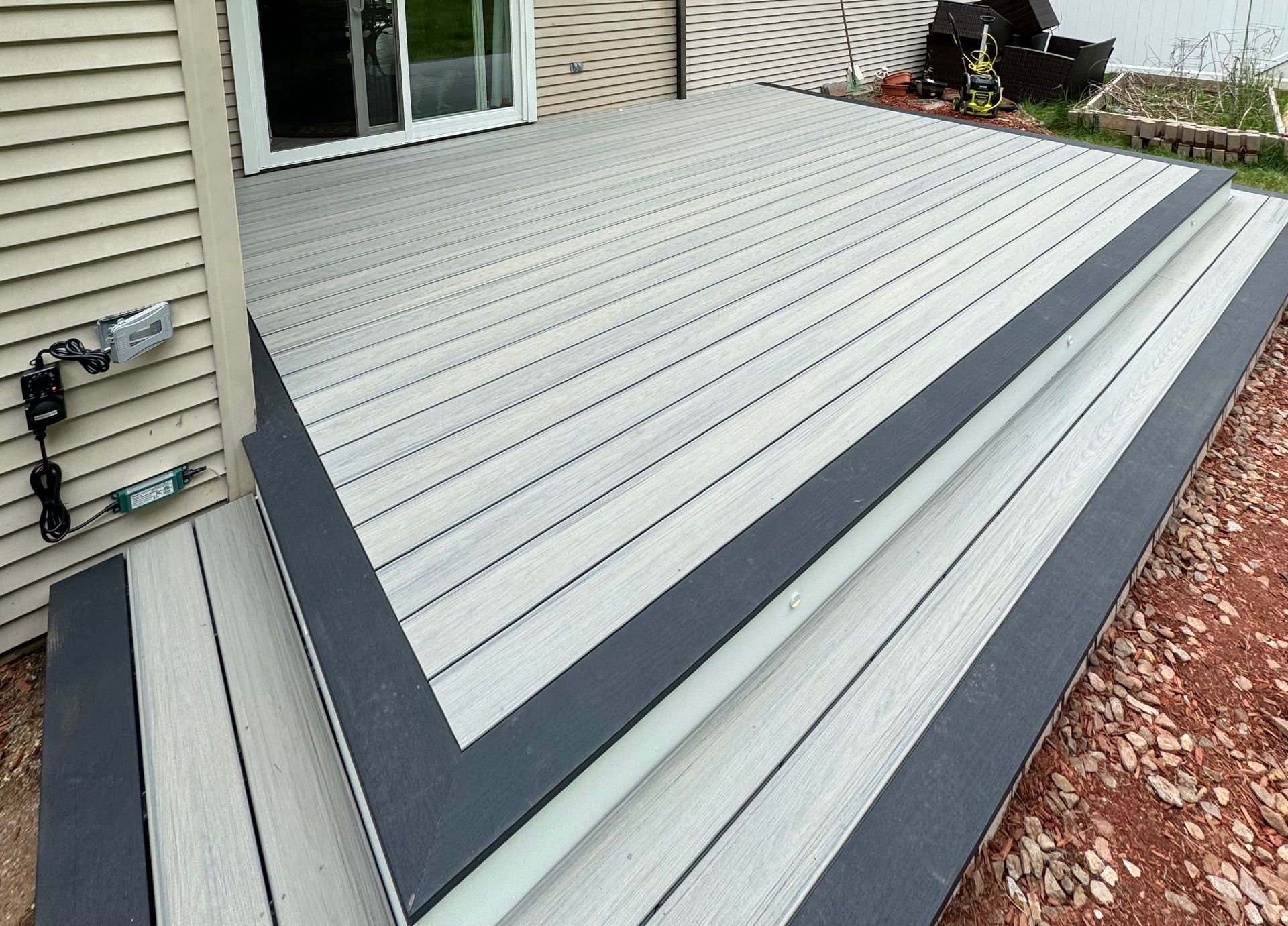 Composite deck with gray boards and dark trim, steps leading down to a yard.