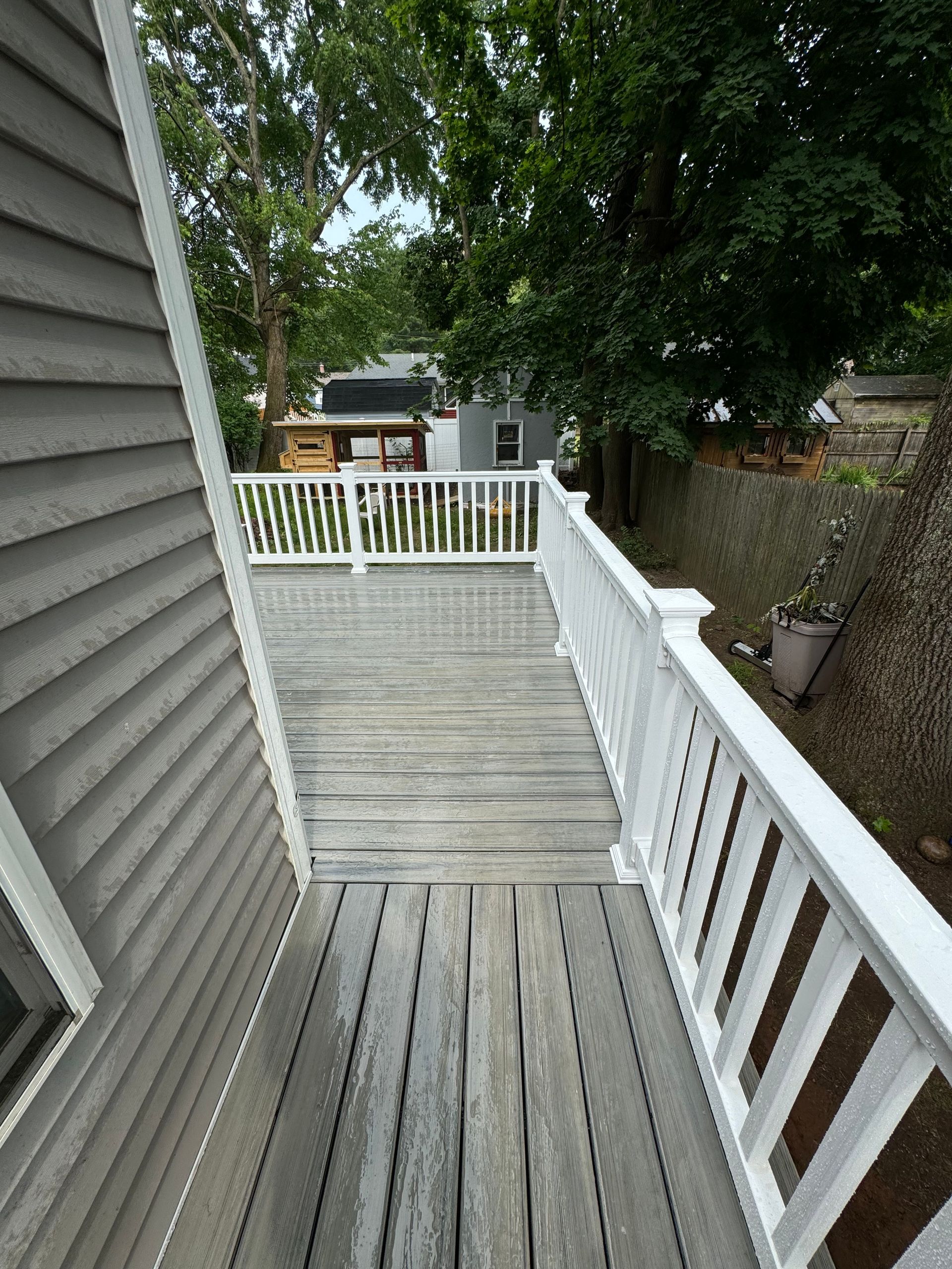 A wooden deck with a white railing leading to a house.