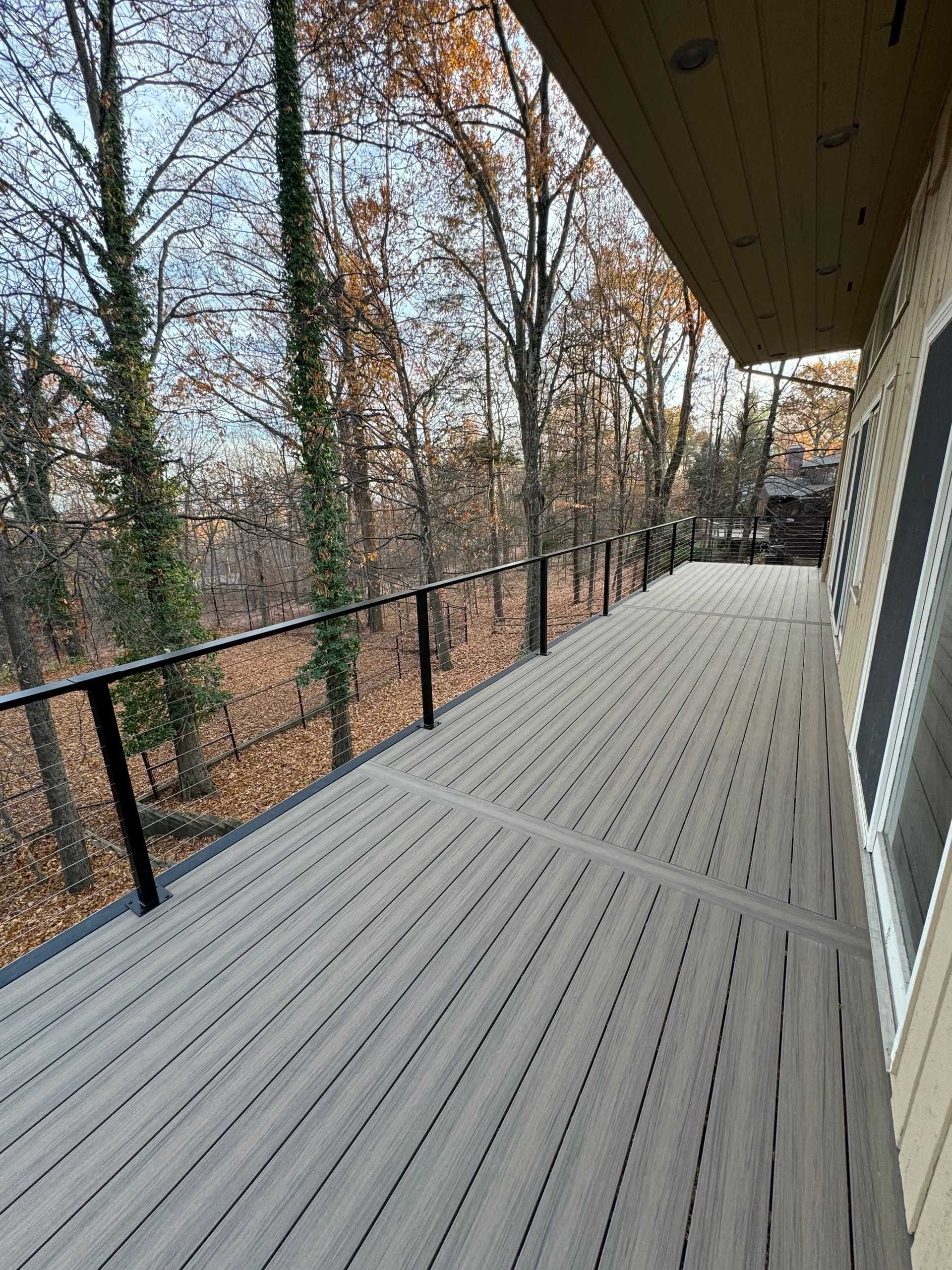 A large deck with a railing and trees in the background.