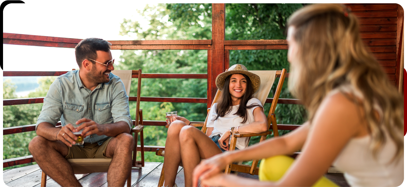 A group of people are sitting on a porch talking to each other.