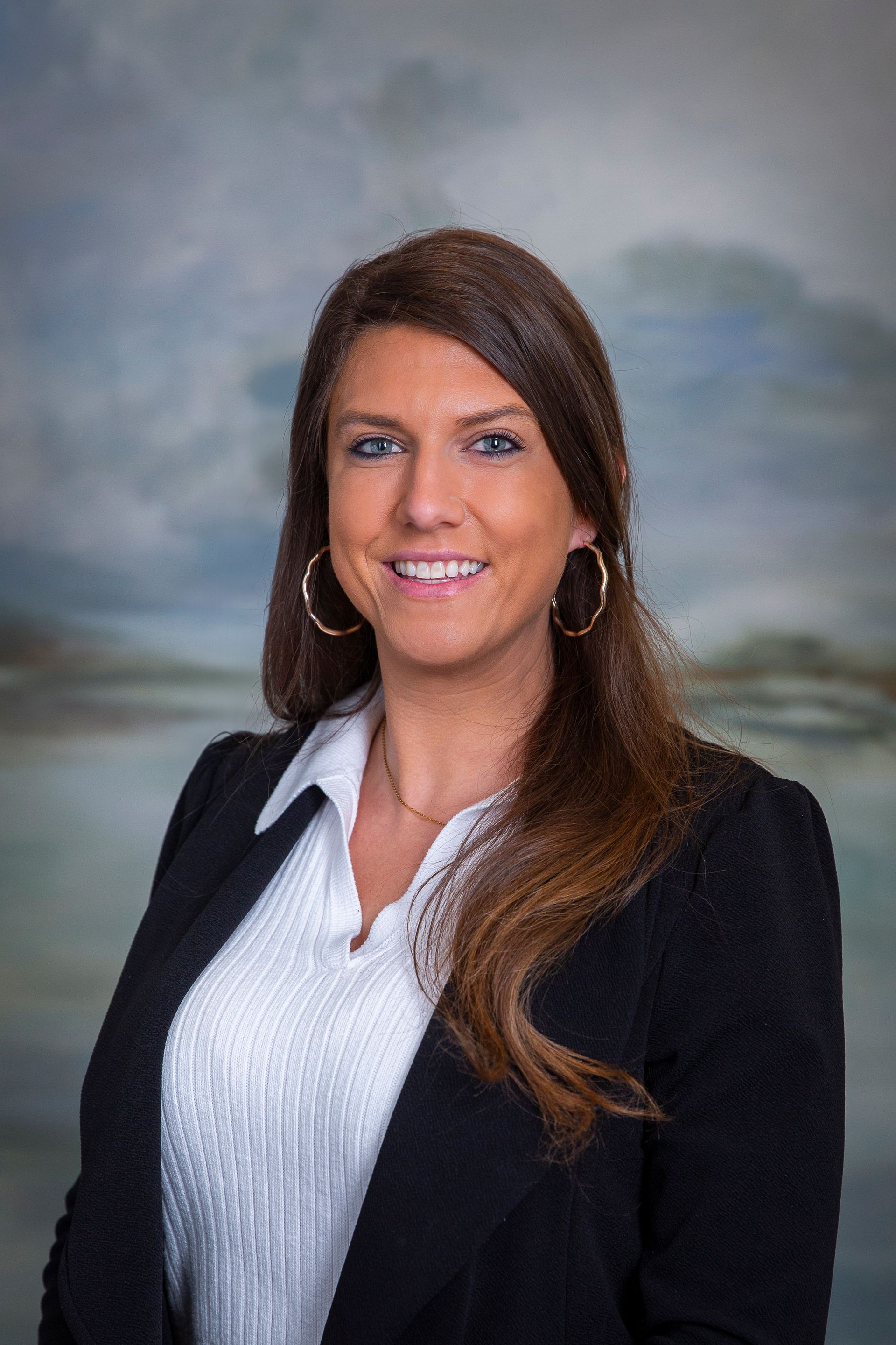 A woman in a black jacket and white shirt is smiling for the camera.