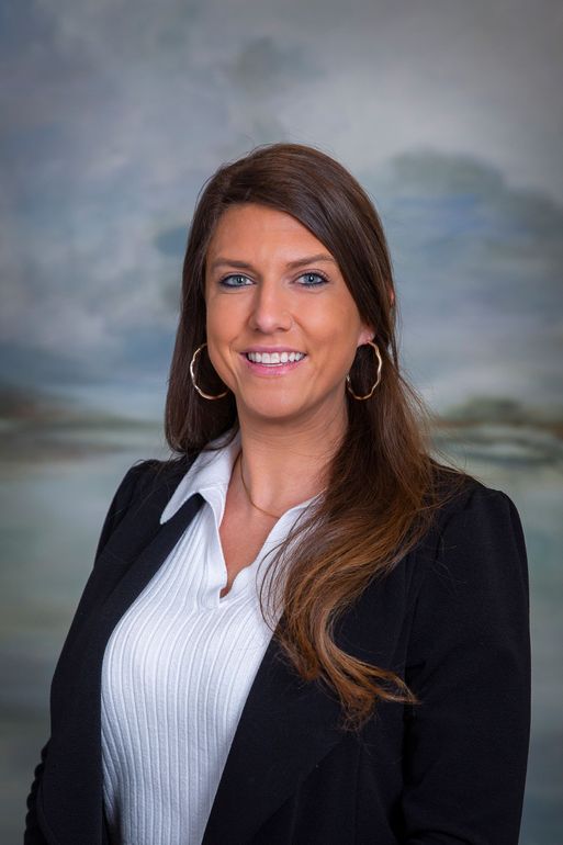 A woman in a black jacket and white shirt is smiling for the camera.