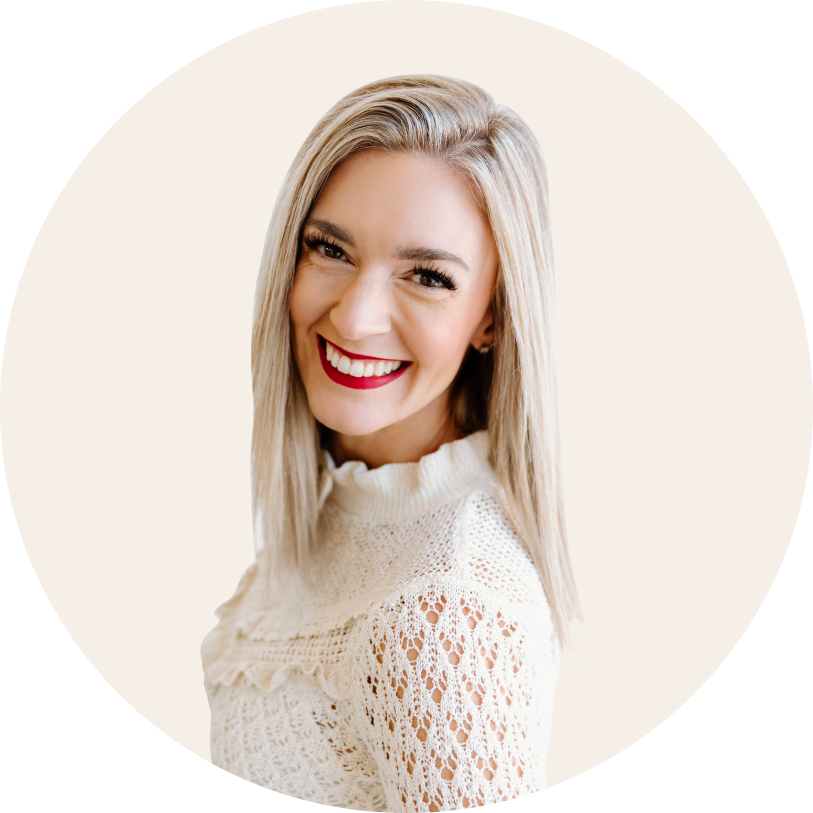 A woman wearing a brown leather jacket and a white shirt is smiling.