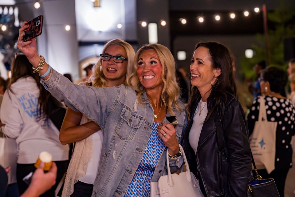 Friends taking a selfie under string lights on the plaza